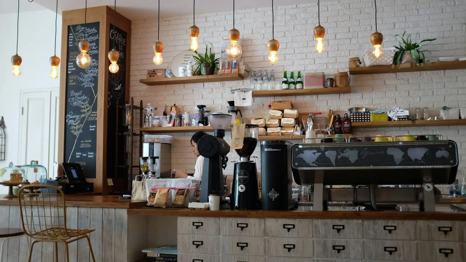 Comptoir en bois clair avec machine à espresso, moulins et ampoules suspendues